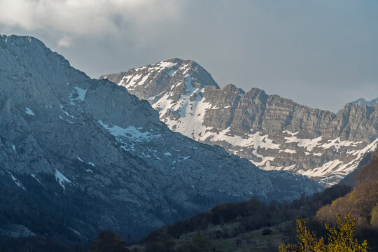 Rugged mountain range with snow under cloudy skies, Savnik