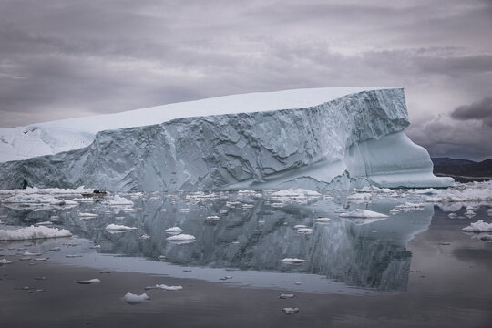 Massive iceberg towers over a tiny boat in Greenland