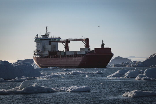 Container ship navigating through icy arctic ocean