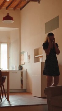 Distressed woman crying after receiving bad news, feeling sadness, despair, and emotional pain alone in her apartment living room, experiencing grief and heartbreak. Vertical video