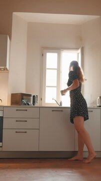 Young caucasian couple having a relaxed conversation in a bright, sunlit kitchen while enjoying their morning coffee and sharing a moment of genuine connection and laughter together. Vertical video