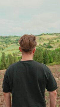Young adventurous man exploring the tuscan countryside, enjoying the breathtaking italian landscape view from a hill, traveling and contemplating the beauty of nature. Vertical video 