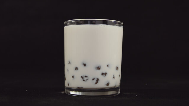 White liquid drink with black tapioca pearls settled at the bottom of a clear glass