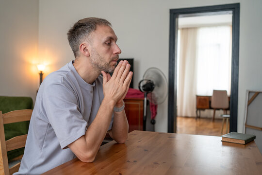 Anxious man uses grounding to calm himself while facing difficult choice, uncertainty and overthinking, coping with emotional exhaustion alone at home.
