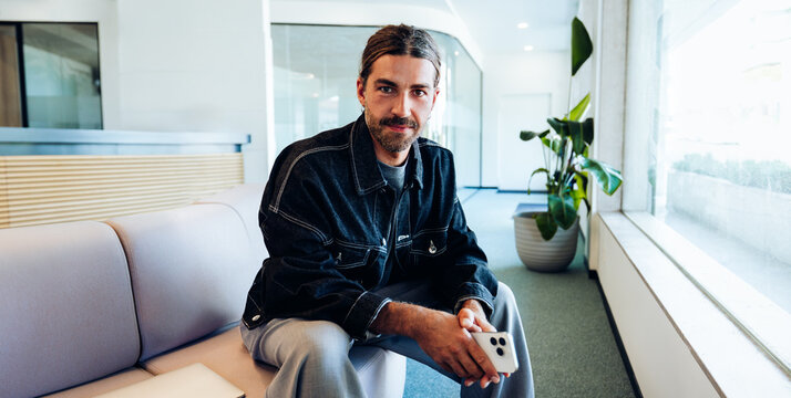 Man waiting in office lobby with smartphone