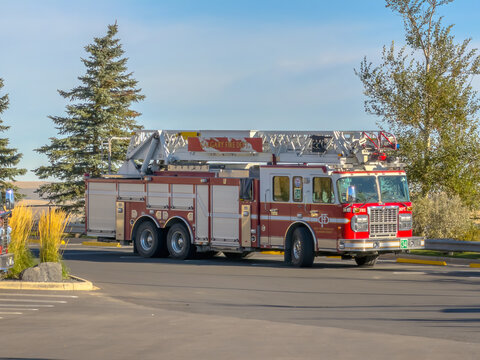 Calgary, AB, Canada. Oct 1, 2026. Side view of a Calgary Fire Department ladder truck parked outdoors on an asphalt lot on a sunny day.