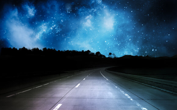 Romantic night road trip on asphalt highway under magical starry galaxy sky