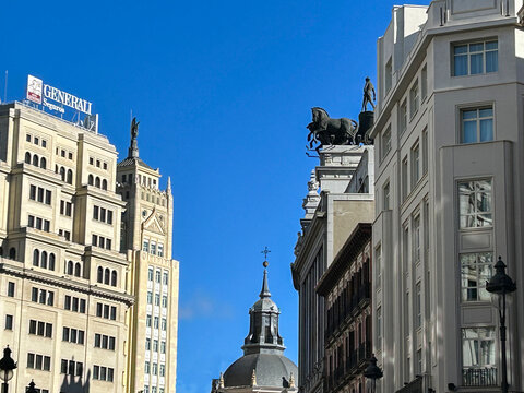 View of the street Calle de Alcala with its distinctive historic buildings and a church dome. Madrid. Spain.