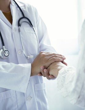 Doctor holding hands of patient to give comfort support and reassurance in hospital clinic for medical healthcare compassion concept