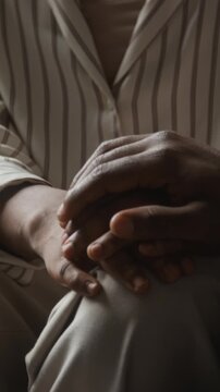 Vertical shot of unrecognizable African American adults holding hands in comforting gesture. Footage suitable for mental health therapy, grief counseling, and caregiver campaigns