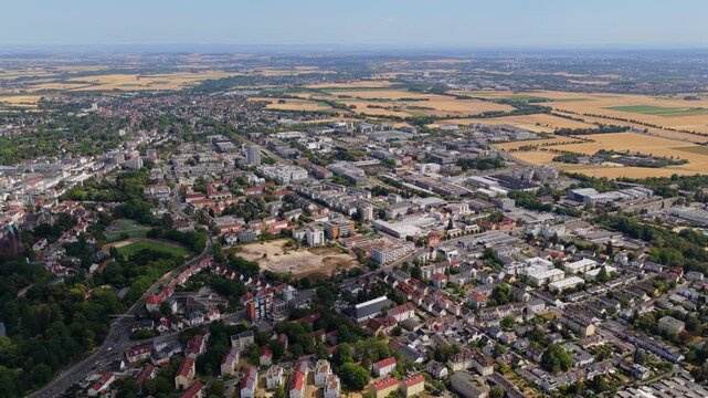 High wide slow drifting aerial over Bad Homburg cityscape toward golden Wetterau farmland in hazy summer daylight, Bad Homburg, Hesse, Taunus, Germany