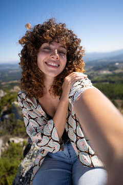 White woman taking smiling selfie with scenic Pico Sacro mountainous
