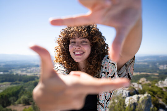 Smiling white woman framing hands with mountain nature background