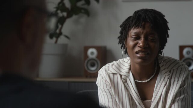 African American woman talking emotionally with therapist during consultation over shoulder shot. Footage ideal for mental health and psychological counseling campaigns