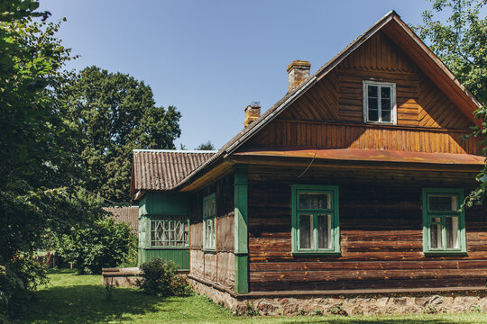 Rustic wooden country house in lush green summer garden. Nostalgic atmosphere of rural life. Traditional log cabin, escape from city life, simplicity, connection to nature, countryside lifestyle.