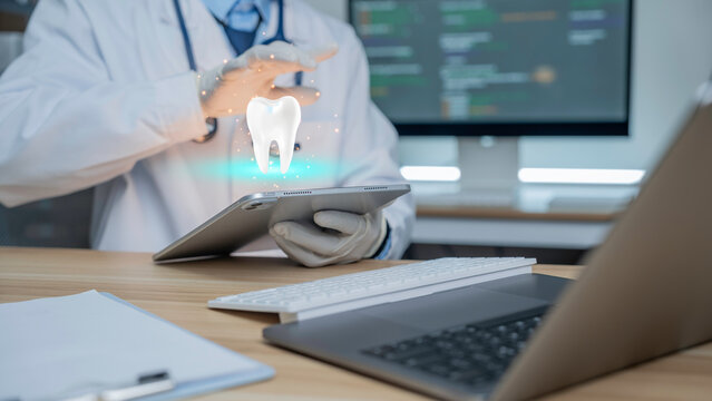 Modern dentist is using a laptop displaying a digital holographic image of teeth, showcasing advanced dental technology and oral health innovation.