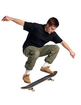 Homme en t-shirt noir ample, pantalon cargo kaki, chaussettes blanches et baskets camel, en plein saut sur un skateboard, genoux pli&eacute;s, bras &eacute;cart&eacute;s et regard dirig&eacute; vers la planche