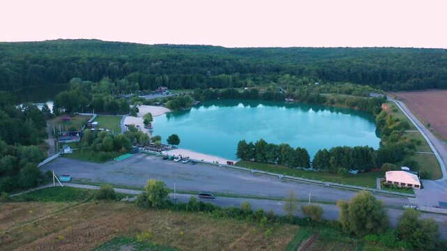 The lake is located in an abandoned quarry with blue water. Scenic aerial view of an abandoned quarry with clear blue water transformed into a public beach and recreational park with swimmers.