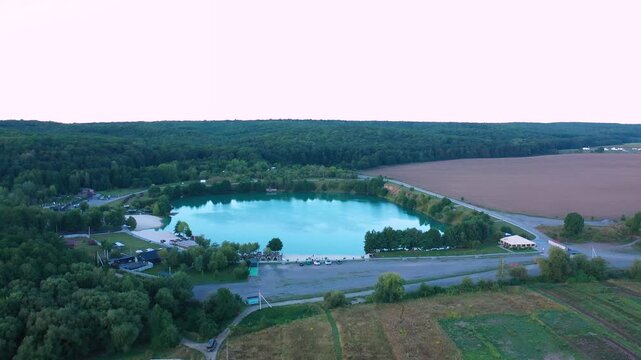 The lake is located in an abandoned quarry with blue water. Scenic aerial view of an abandoned quarry with clear blue water transformed into a public beach and recreational park with swimmers.