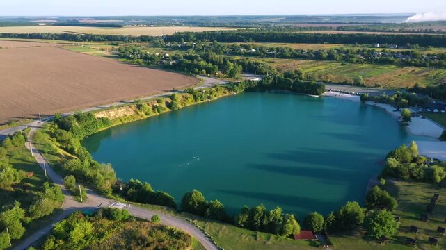 The lake is located in an abandoned quarry with blue water. Scenic aerial view of an abandoned quarry with clear blue water transformed into a public beach and recreational park with swimmers.