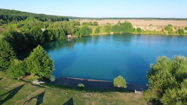 The lake is located in an abandoned quarry with blue water. Scenic aerial view of an abandoned quarry with clear blue water transformed into a public beach and recreational park with swimmers.