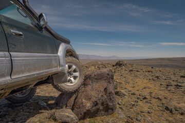 Close up low angle view of an off-road 4x4 suv car climbing onto a large rock boulder, overlanding concept  © ANDREY