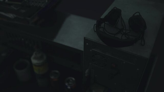 Headphones resting on amplifier and console, dim studio light, cables coiled, mixing hardware, worn foam pads, intimate listening space, postproduction