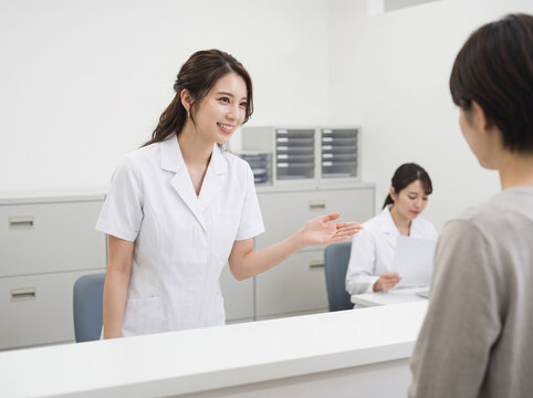 病院の受付で患者を丁寧に案内する医療スタッフの女性