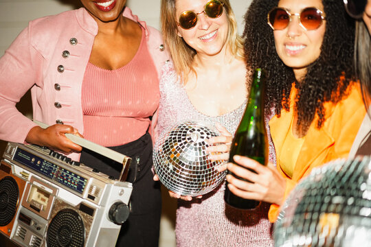 Group of multiracial girls dancing, drinking champagne and listening music outdoor - New yea'rs eve party and street nightlife concept - Main focus on right blond girl face - UGC flash content