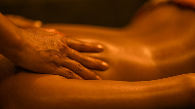Professional therapist performing a relaxing back massage in a warm dimly lit spa environment