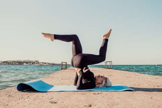 Yoga Woman Beach Pose Fitness - Woman doing yoga headstand on a mat at the beach.