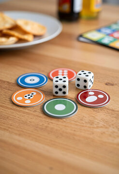 Family game night and social leisure, board game pieces and dice on a wooden table with snacks for entertainment and home recreation activities