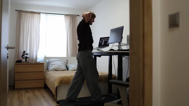Young trader finally understands how the stock market works and celebrates his progress while walking on a treadmill after mastering new financial trading concepts at home