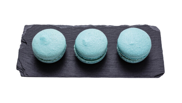 Three light blue macarons arranged on a dark slate platter, isolated on transparent background