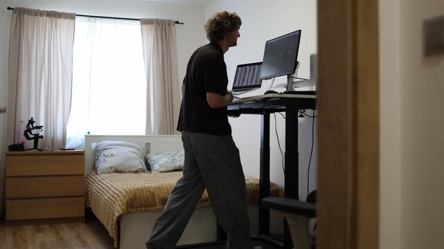 Young man works on a computer while walking on a treadmill combining daily tasks with gentle exercise to stay active and support a healthier routine while working at home