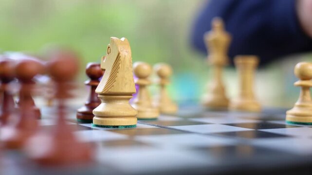 Male hand close up - chess player makes a move with the knight. Man analyzes the situation on the board and makes a move with the knight. Close-up vertical 4k footage.
