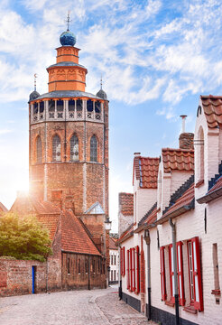 Medieval houses over in Bruges Belgium. Beautiful exteriors with trees and flowers. vintage tower architecture. Sunset evening time..
