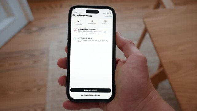 A weekly email security report lists quarantined messages and blocked spam. Point of view shot with the phone held in the hand. Interface in German. Useful for corporate IT communication.