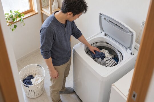 洗濯機を回す前に洗濯物の量を確認する男性