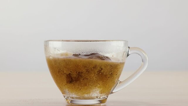 Instant Coffee Powder Pouring and Dissolving in Hot Water Glass Cup