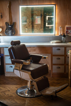 Cozy interior of barbershop with classic vintage chairs, illuminated mirrors and professional grooming tools arranged on counters for clients, indoor setting of hair salon with stylish furniture.