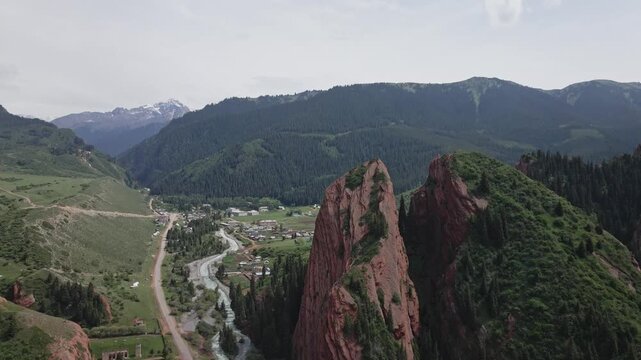 Aerial drone view of a towering red rock formation split by a deep crevice in Jeti Oguz Gorge, Kyrgyzstan