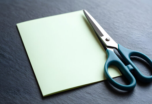 A pair of scissors beside a plain cut card on a table