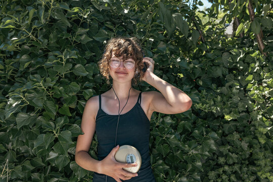 A smiling girl listens to music with a portable CD player outdoors