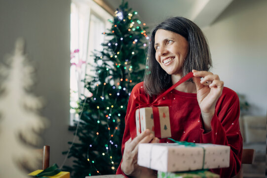 Smiling woman wrapping a Christmas gift at home