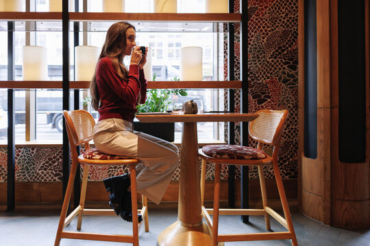 Young woman drinks coffee at a hotel bar table