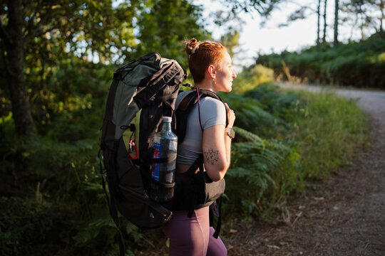Woman hikes on a forest trail with a heavy backpack