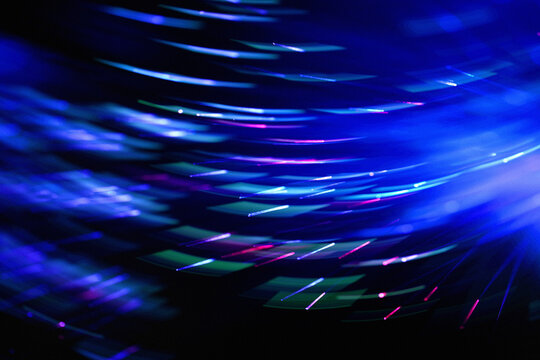 Glowing blue optic fiber cables create abstract light trails
