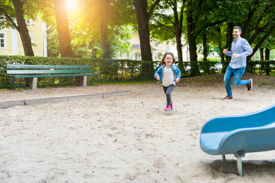 Father running with daughter on playground