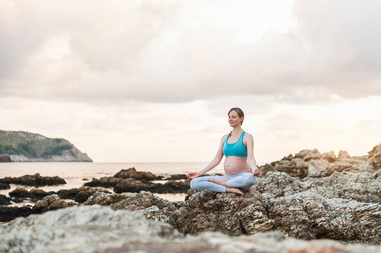 Pregnant woman practising yoga at the sea
